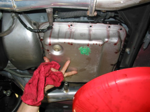 While holding and tipping the tranny pan towards your catch/drain pan, carefully remove the last bolt.