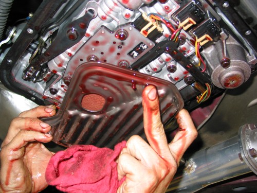 After you have let the fluid drain for a while, you can remove the transmission filter.  Depending on what kind of transmission you are dealing with you may need a socket to do this or you may not.  In my case, the filter basically "snaps" in and is not held in place by any bolts.  Simply grab the filter and twist it slightly back and forth and then carefully remove the filter.  I say carefully because you do not want to damage the seal at the neck of the filterif you can help it!